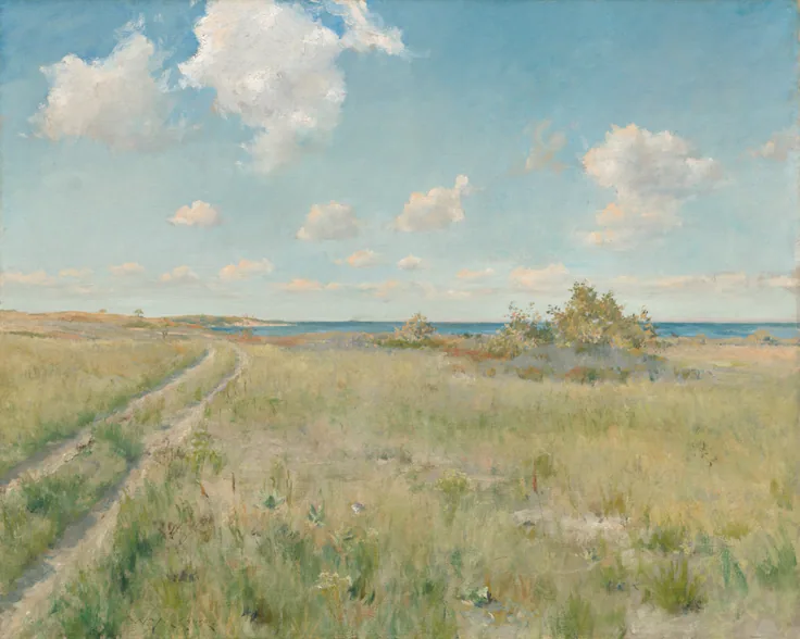 A sandy two-track path through tall summer grass leads to a blue strip of sea under puffy white clouds.