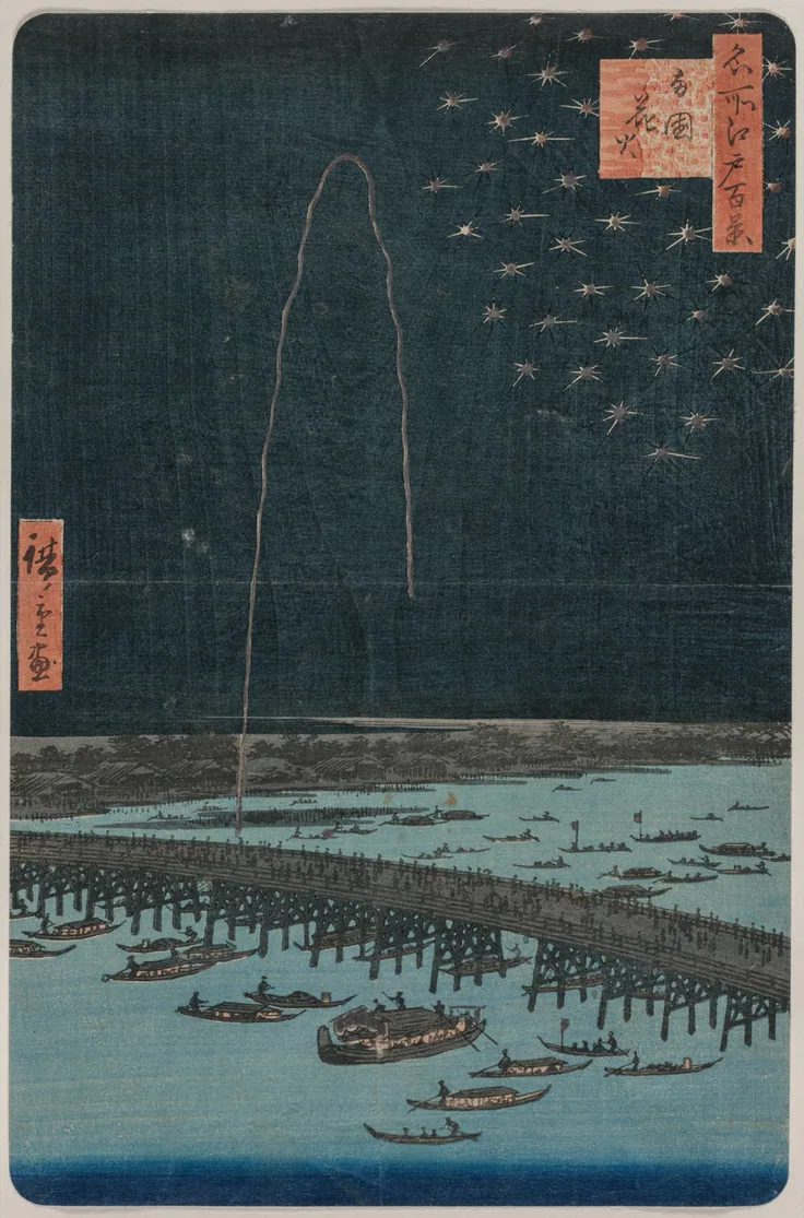 A single rocket trail and starbursts over a crowded wooden bridge and boats on a dark river at night.