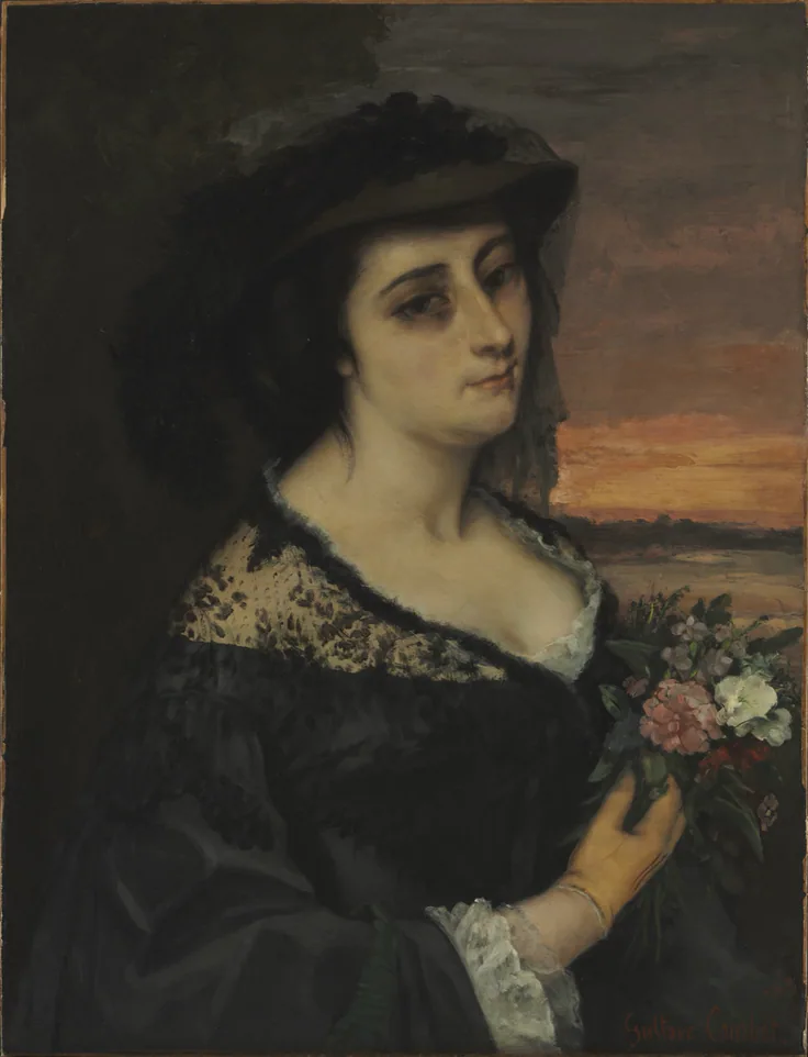 A woman in a black lace dress and hat holds pink flowers, a dusky orange sunset over the sea behind her.