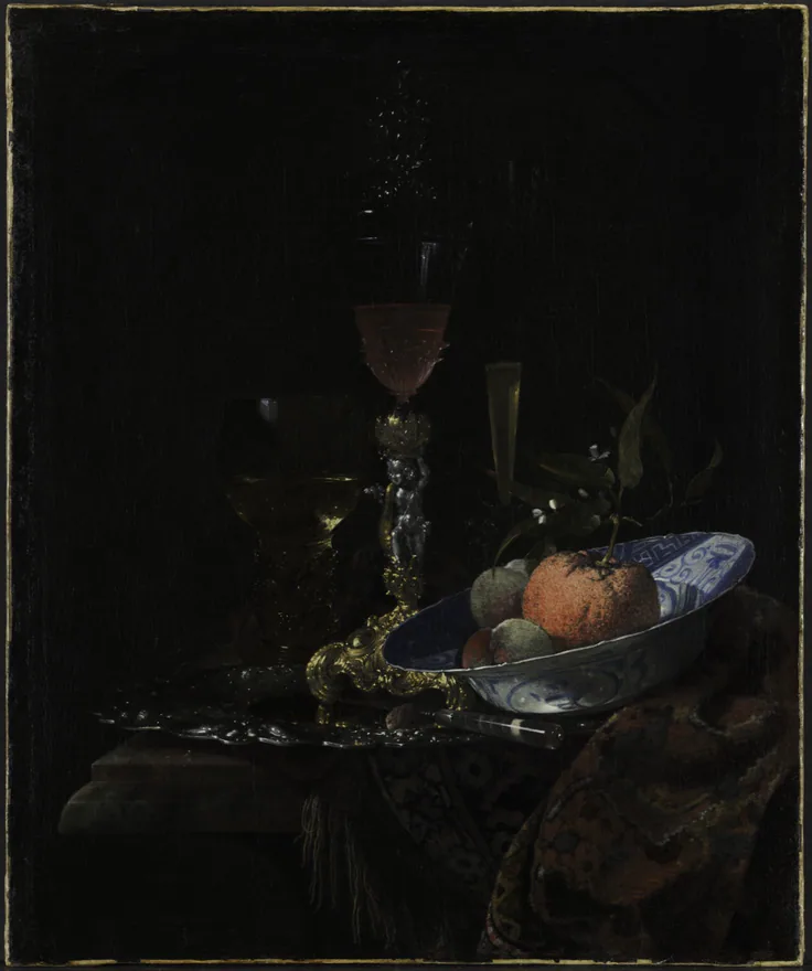 A tall wineglass and a blue-and-white bowl of fruit glint out of near-total darkness; very dark, dramatic still life.