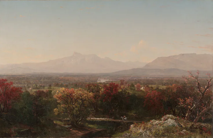 Rolling red and russet foliage below hazy blue mountains and a pale pink sky; a wide, calm valley view.