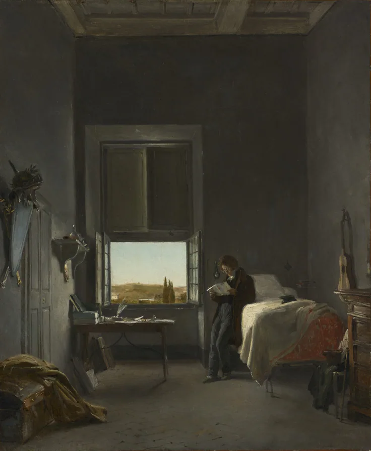 A young man reads by a bright open window in a bare, high-ceilinged room, an unmade bed and drawing board nearby; warm grey shadows.