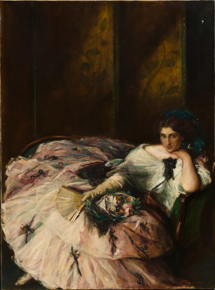 A woman in a voluminous pink ball gown reclines on a dark sofa holding a fan and flowers; rich shadowy brown setting.