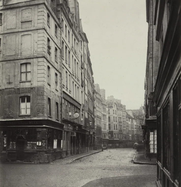 A quiet Paris street of tall shuttered buildings curving out of sight under a white sky; crisp grey tones.