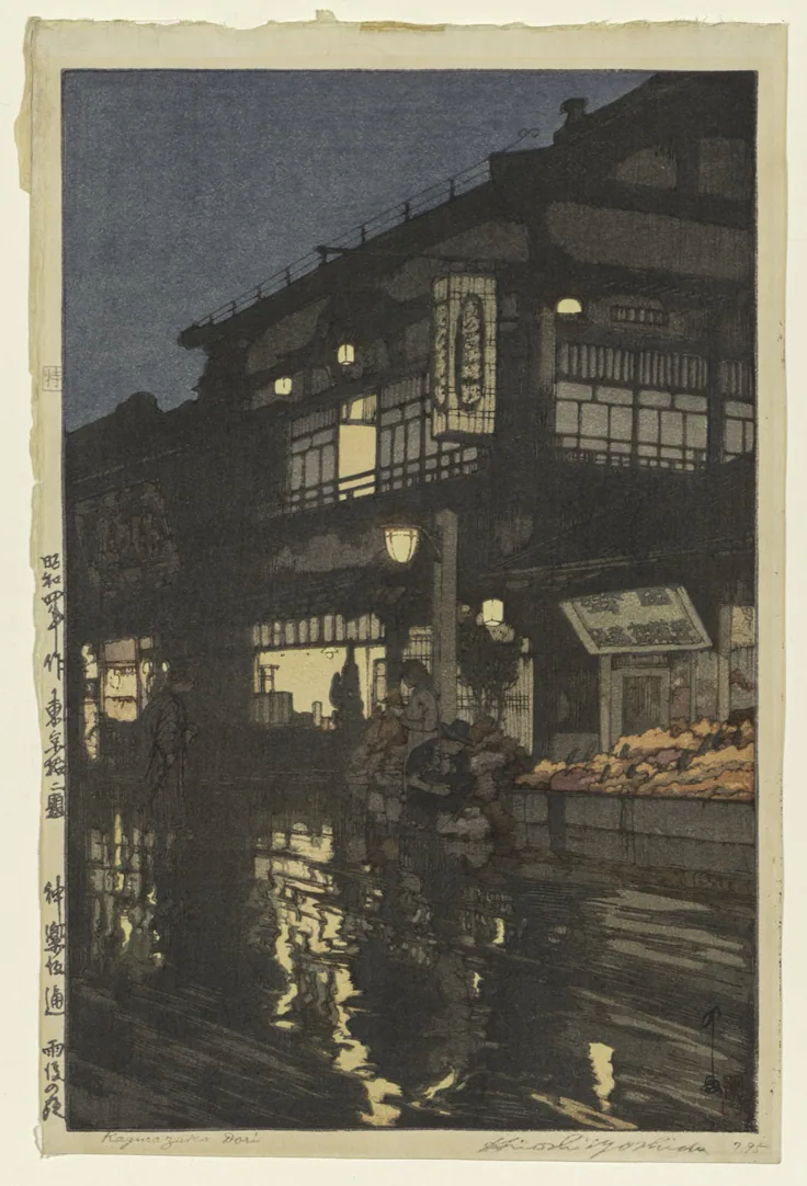 Lit shop windows and lanterns reflect in a wet street at night; deep indigo sky and warm yellow glow.