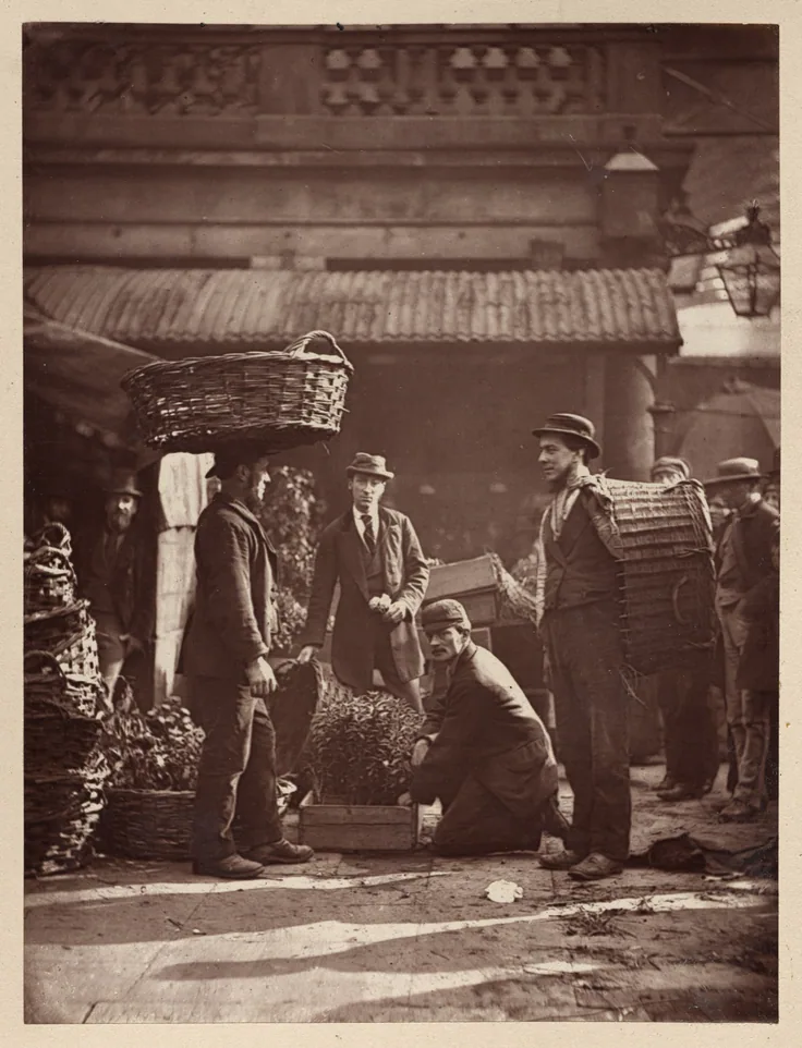 Porters with baskets on their heads stand in the old Covent Garden market arcade; warm reddish-brown woodburytype.