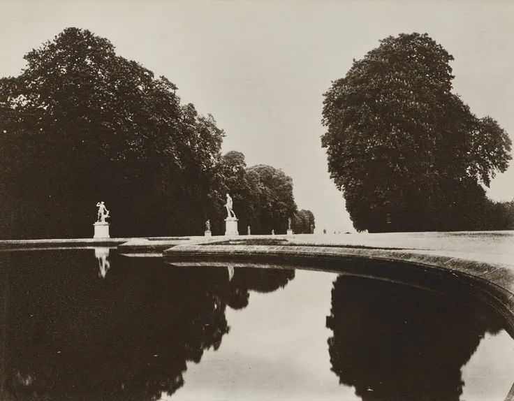 Clipped trees and statues mirrored in a dark formal pool under a white sky; strong symmetrical black and white.